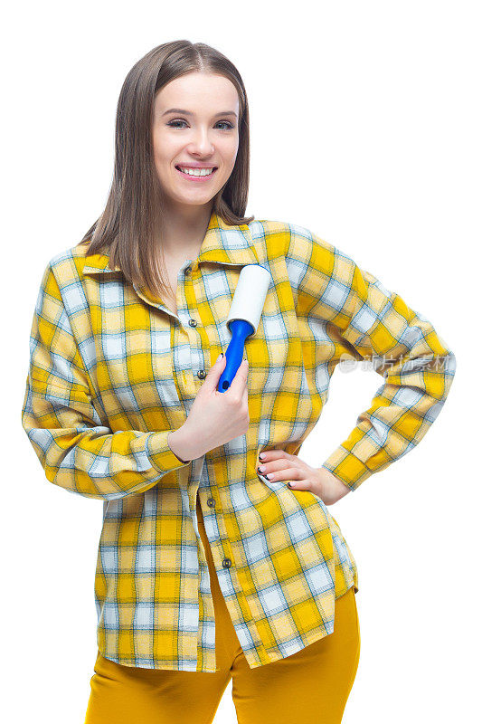 年轻女子的肖像使用一个lint remover清洁黄色格子衬衫的灰尘，头发，绒毛和绒毛，孤立在白色背景
